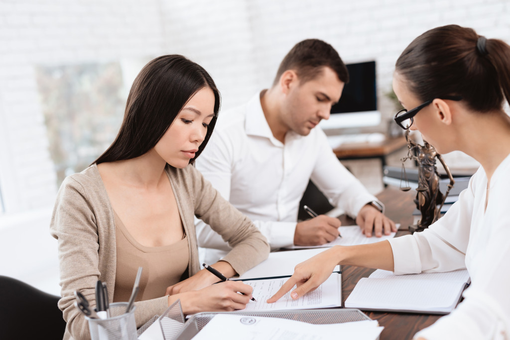 man and woman signing divorce papers with female lawyer instructing them