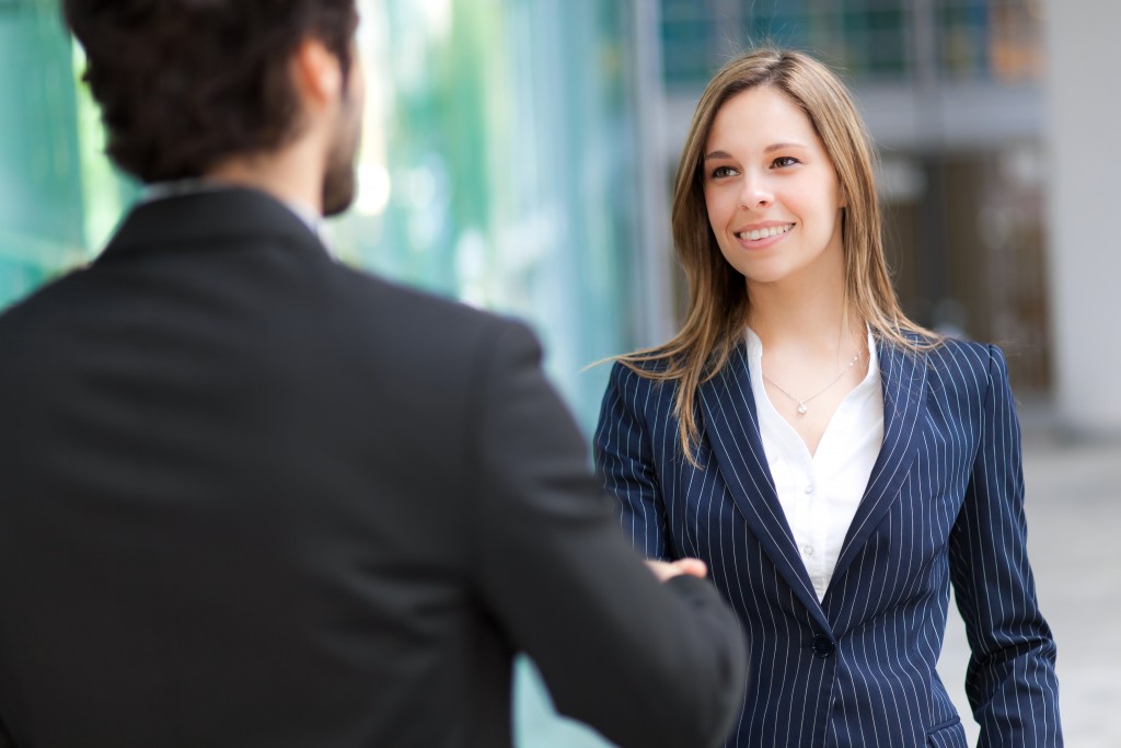 mature career woman confidently shaking hands with a man