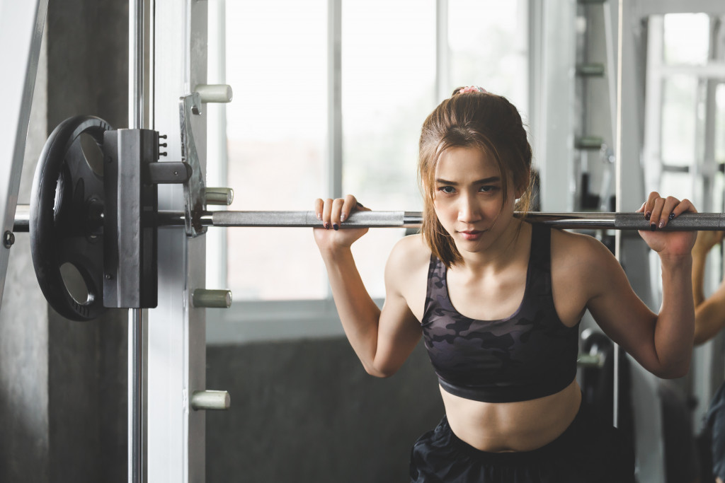 asian woman lifting barbell in gym exercise