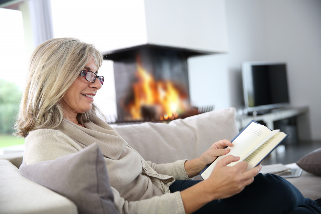 a woman reading a book while sitting on a sofa