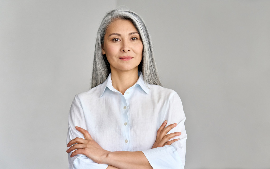 woman with white hair crossing arm to show confidence as a business leader