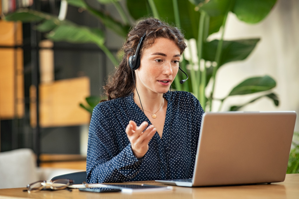 a woman using a laptop wearing headphones in a meeting