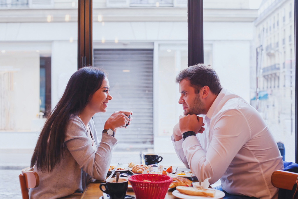 happy couple having lunch in cafe with pastry dishes