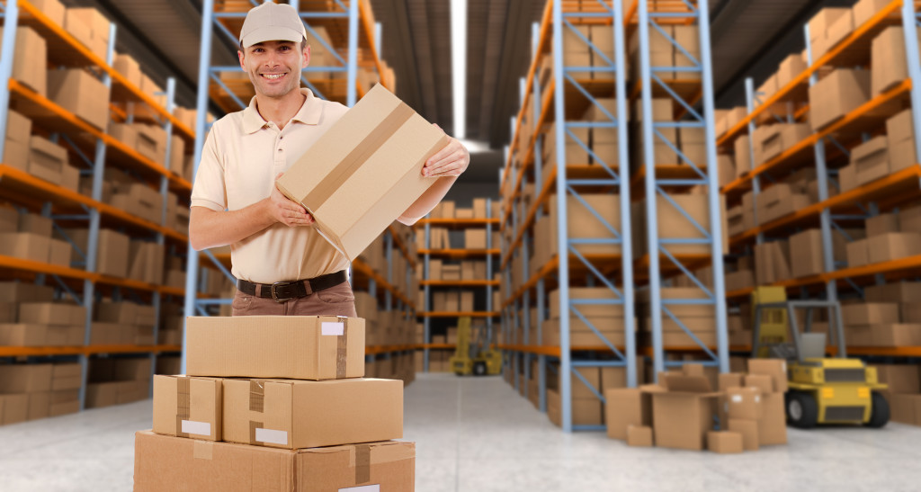 a man in a warehouse full of packages holding a carton box