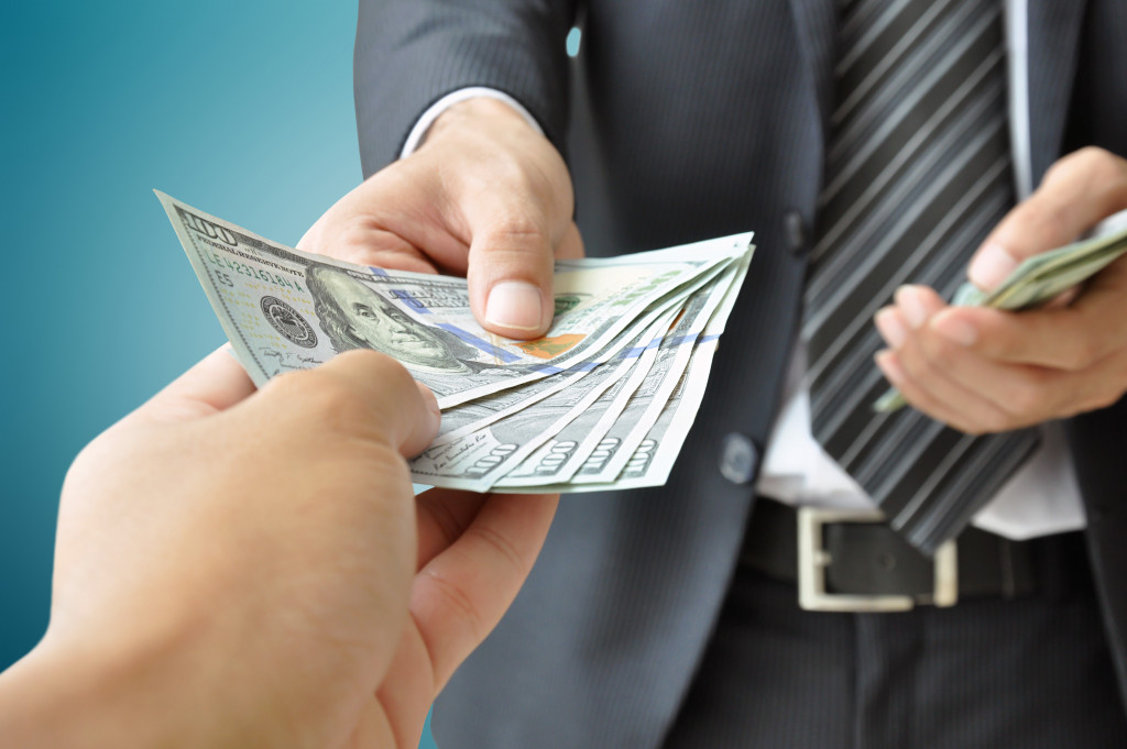 a person in business suit handing money to another person