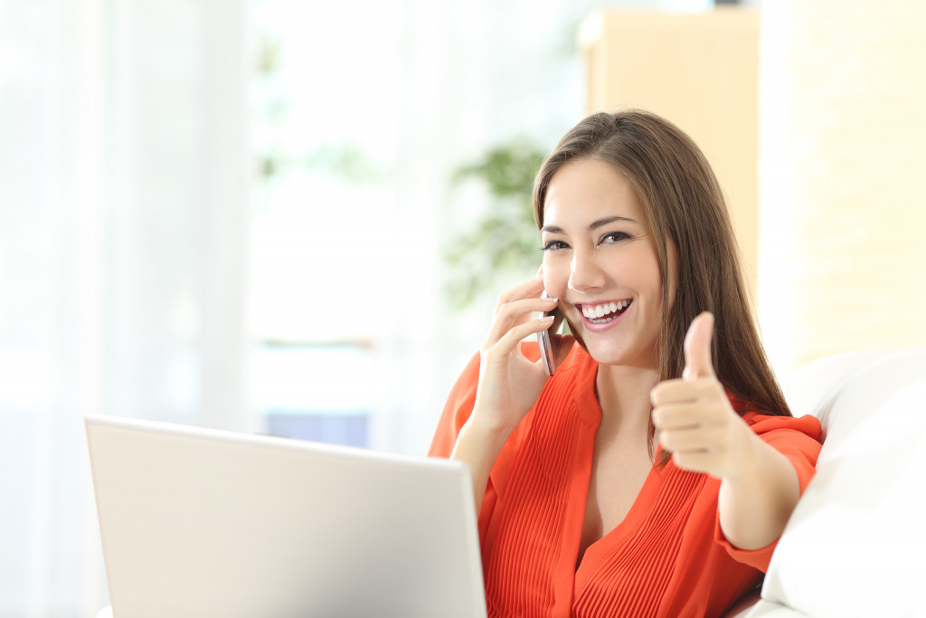 Young woman showing a thumbs up sign while on the phone.