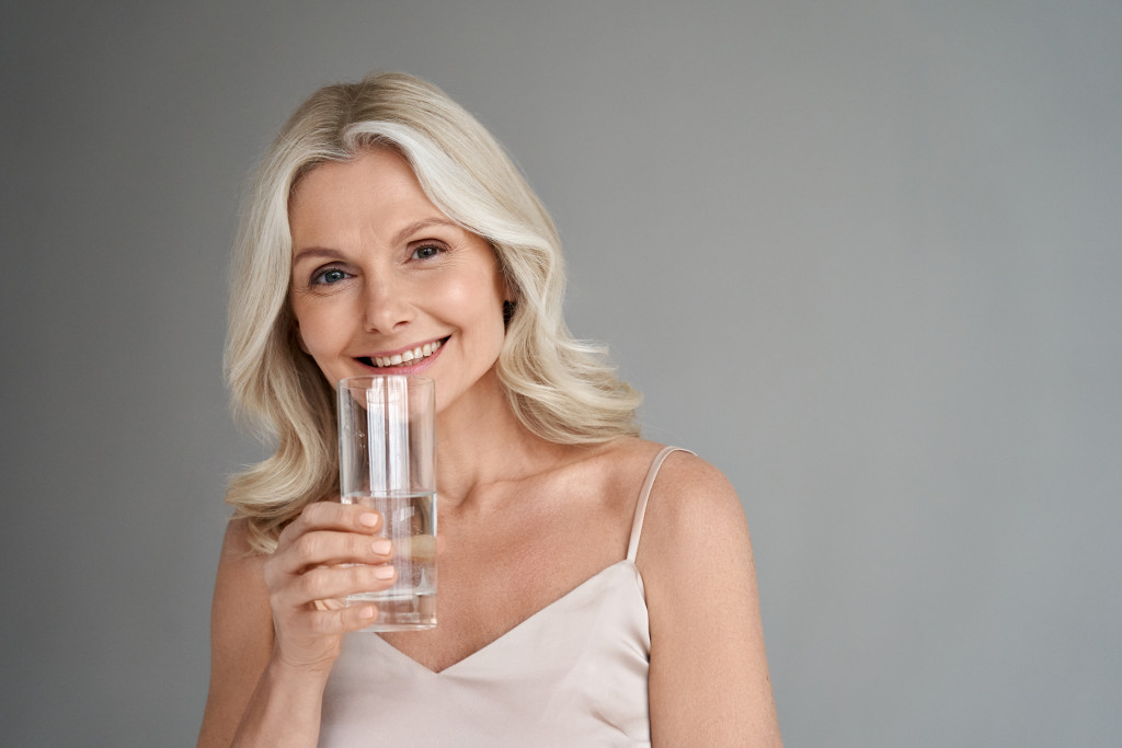 A middle-aged woman holding a glass of water while smiling